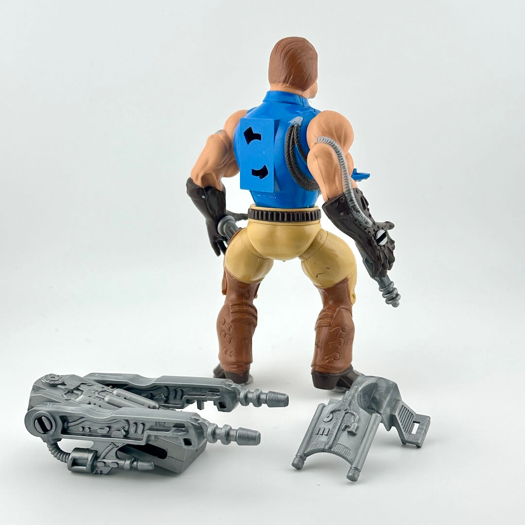Action figure with blue vest and brown pants on a white background with gray accessories.
