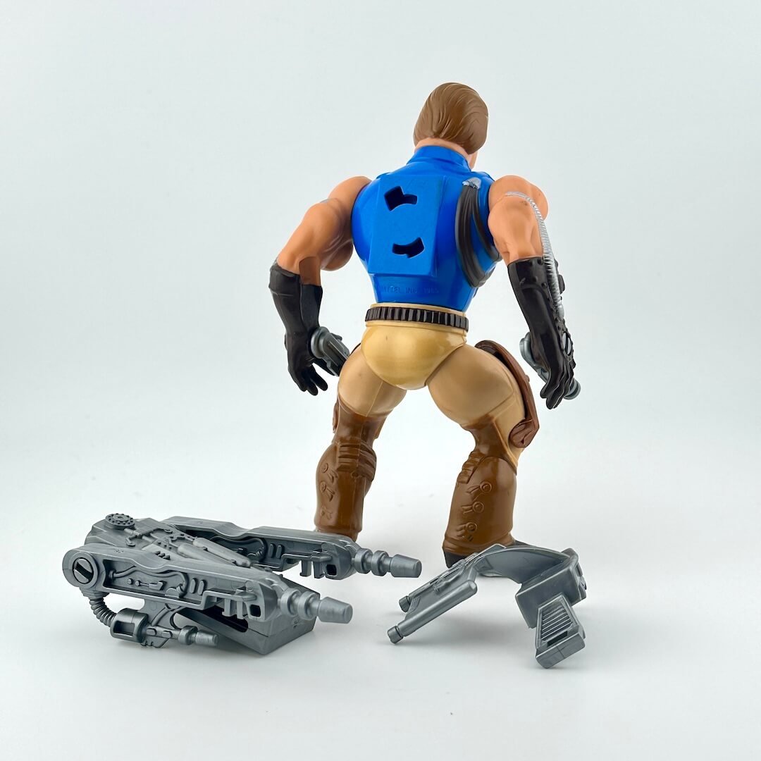 Action figure with blue vest and brown pants on a white background with gray accessories.