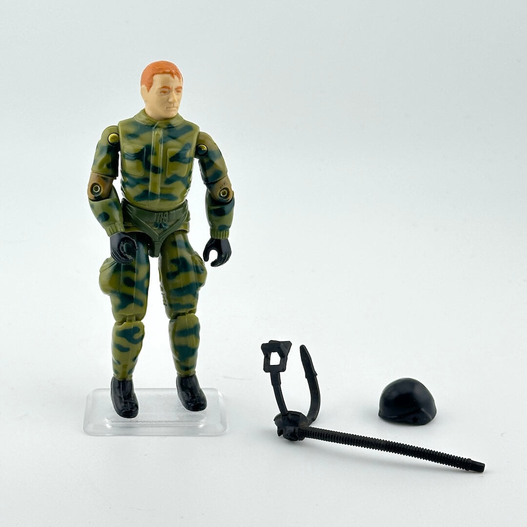 GI Joe action figure in camouflage outfit with accessories against white background. 