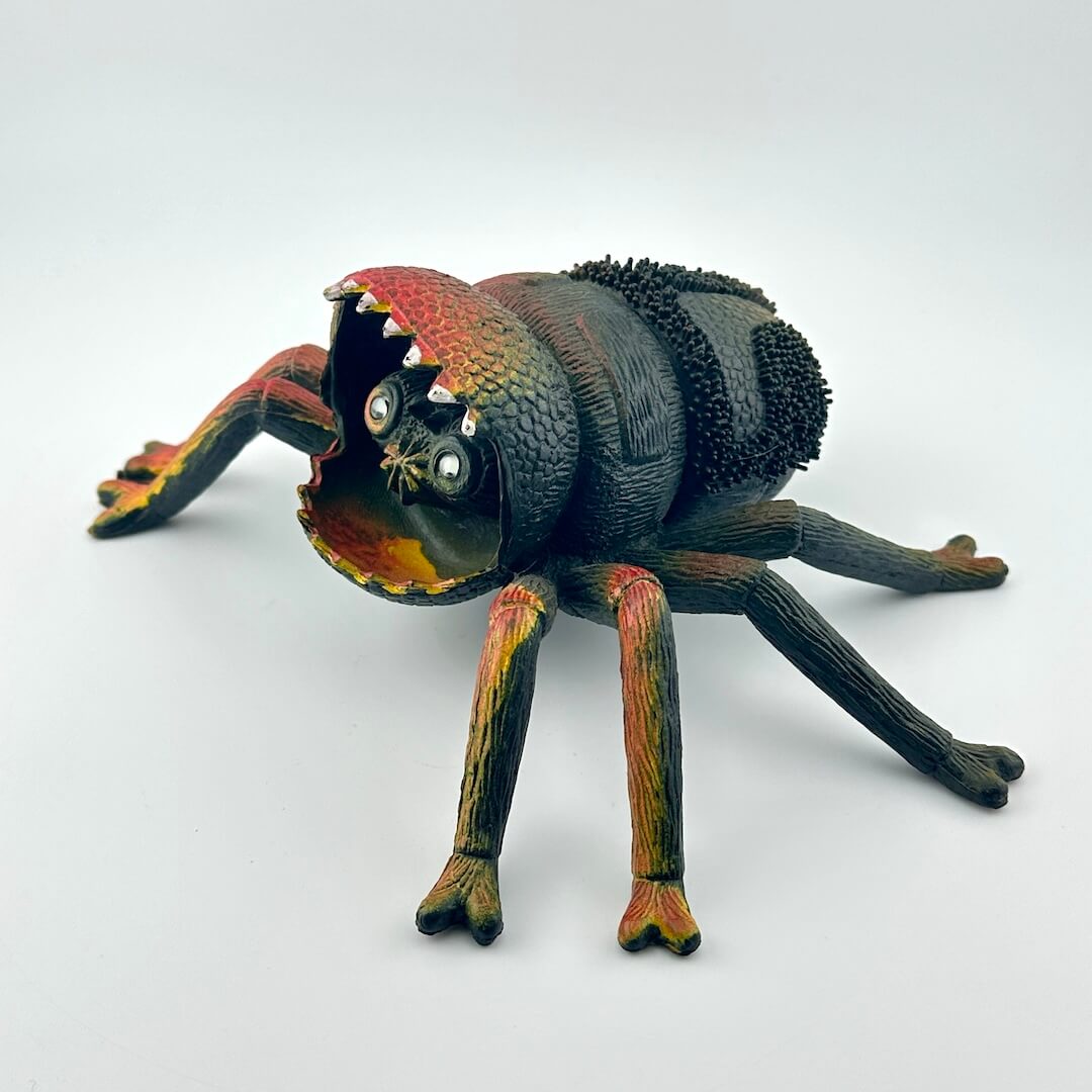 Colorful spider toy with face inside mouth, on a white background