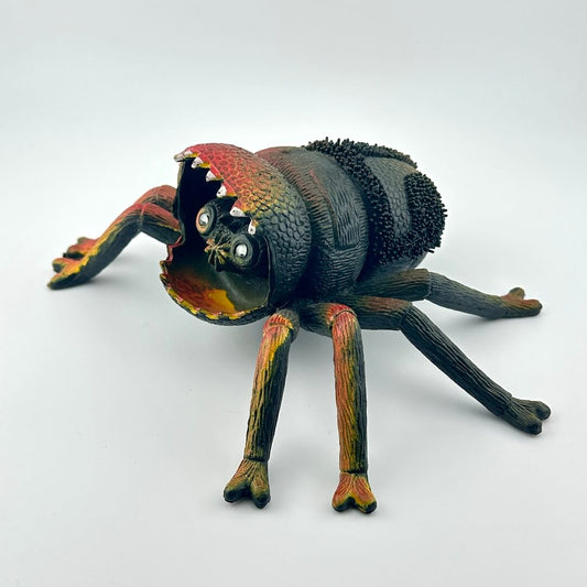 Colorful spider toy with face inside mouth, on a white background