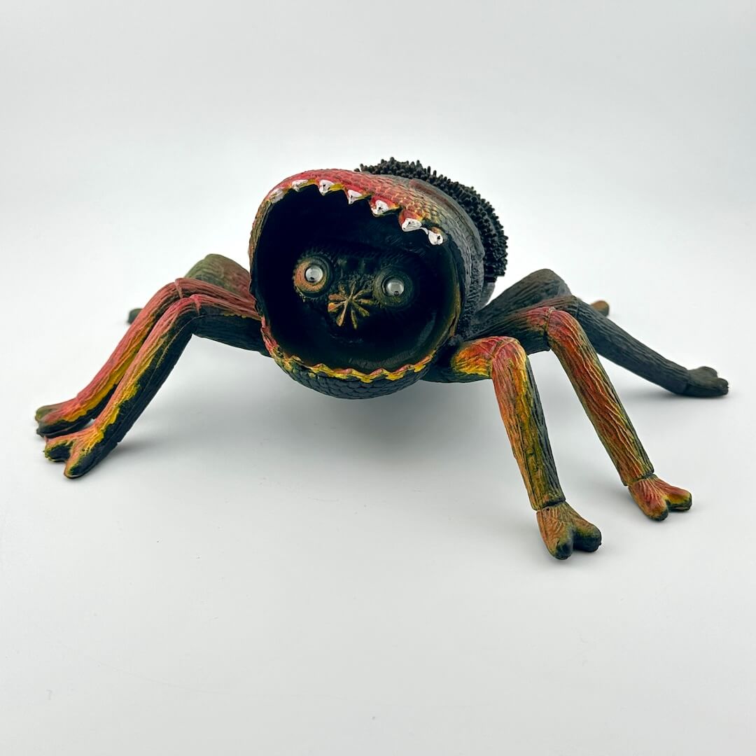 Colorful spider toy with face inside mouth, on a white background