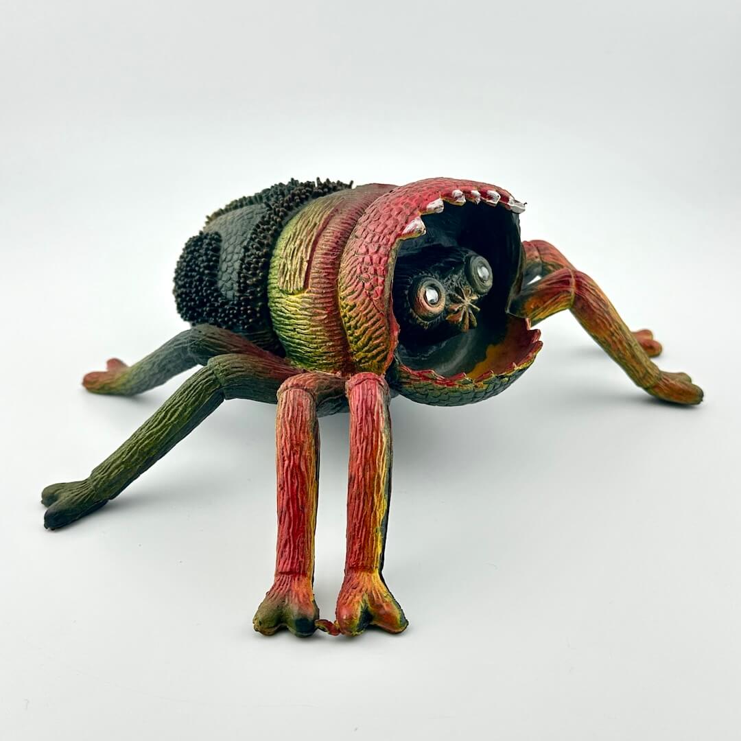 Colorful spider toy with face inside mouth, on a white background