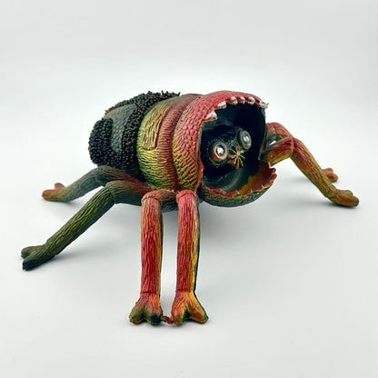 Colorful spider toy with face inside mouth, on a white background