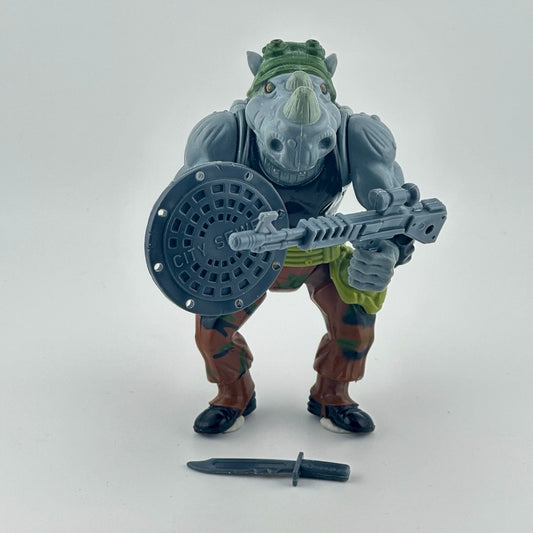 Anthropomorphized Rhino with in brown outfit, grey trash can lid shield, grey gun, and grey knife. Front.