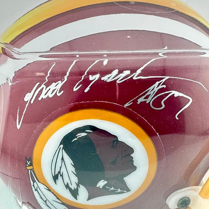 Close-up of a maroon helmet with a Native American profile logo and signature.