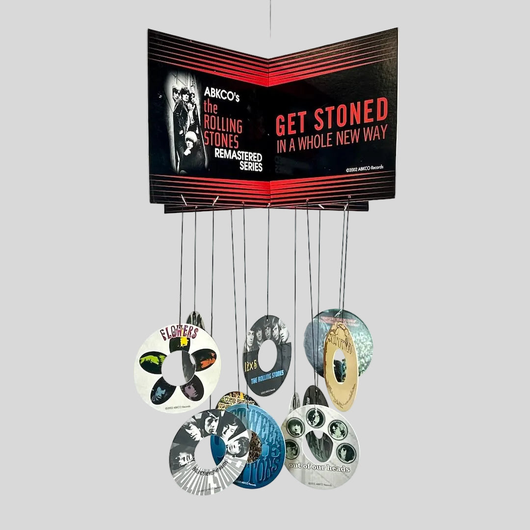 Collection of cardboard records with a promotional poster for The Rolling Stones on a white background