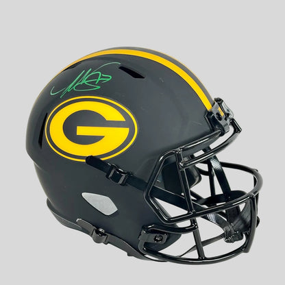 A signed Green Bay Packers full football helmet in matte black with a yellow stripe and large yellow 'G' logo on the side.