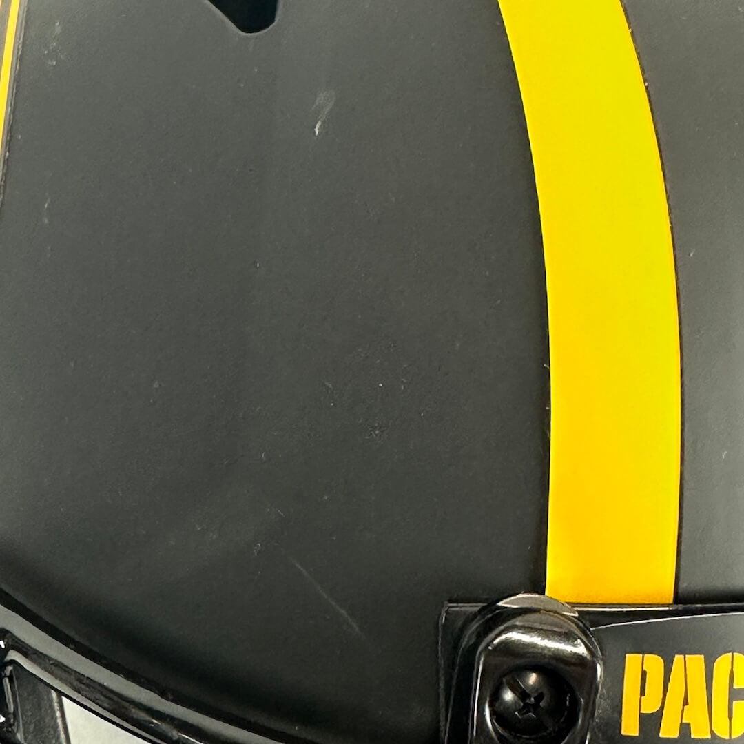 Close-up of a black helmet with a bold yellow stripe running vertically and a couple of scratches. 