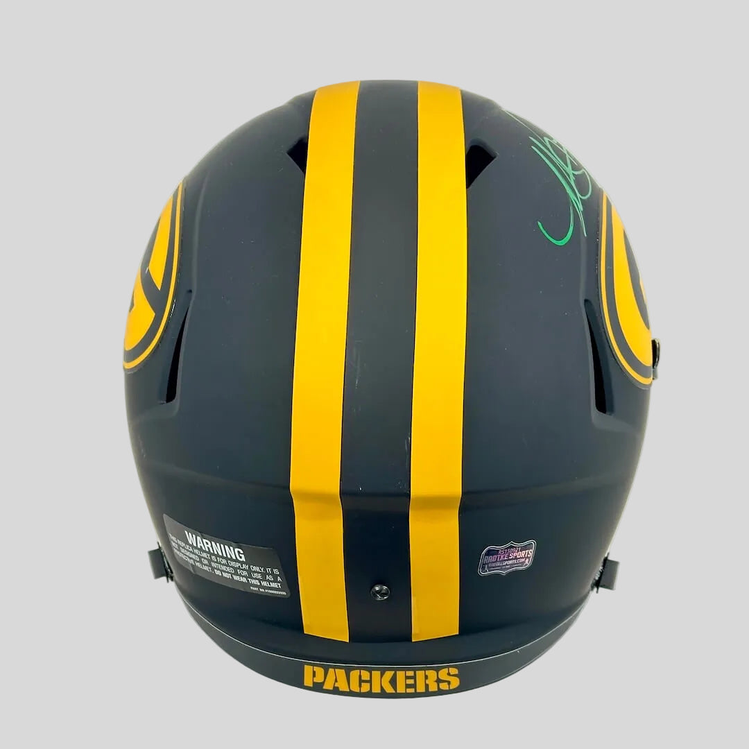 A matte black football helmet with two bold yellow stripes down the center, featuring a green autograph on the side.