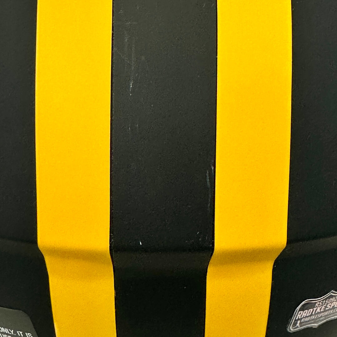 Close-up of a black helmet with bold yellow racing stripes, showing a small sticker on the lower right.