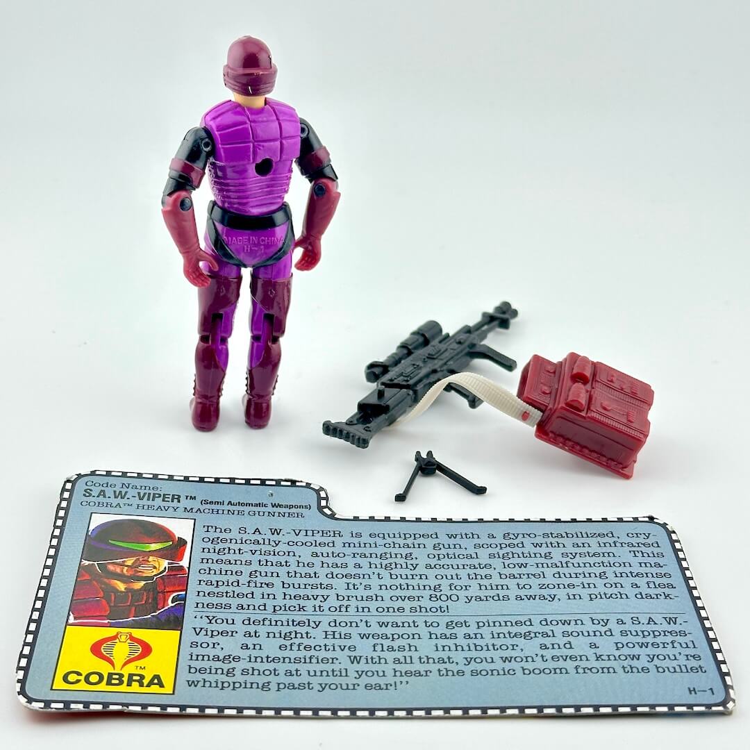 GI Joe action figure with accessories and character card against white background. 