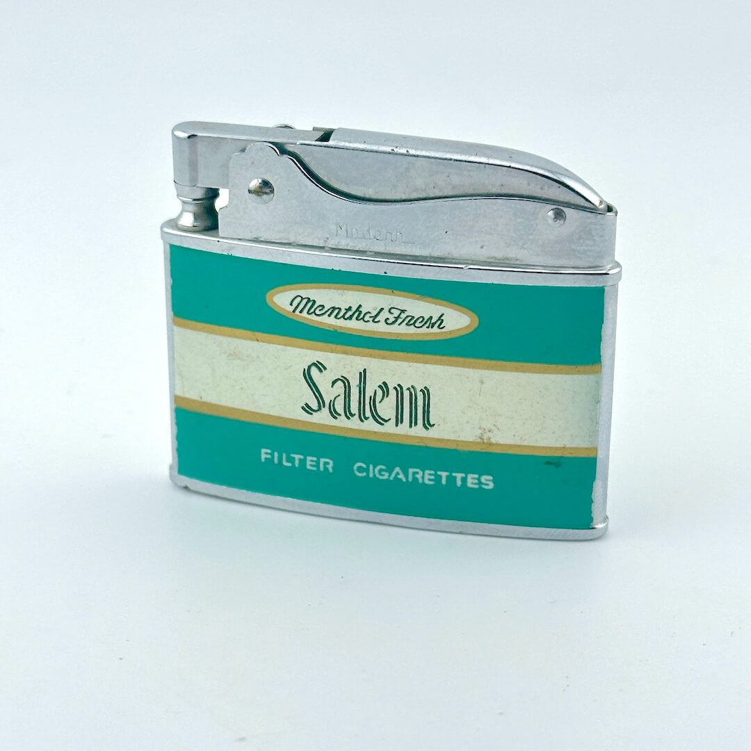 A vintage metal cigarette lighter with a teal and cream Salem filter cigarettes label.