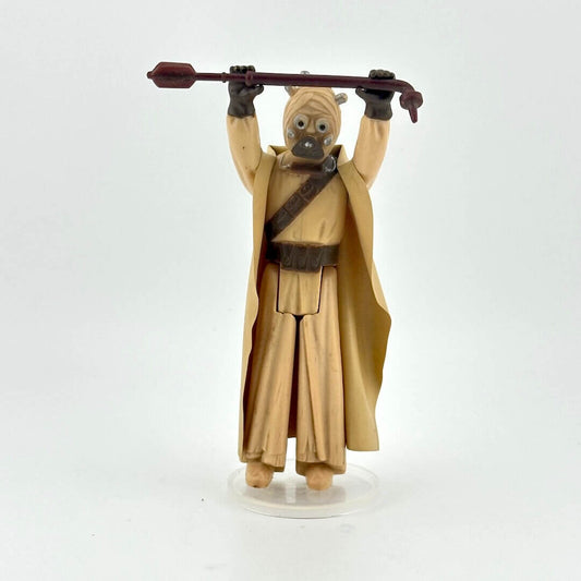 Action figure of Sand Person holding stick aloft in long tan cloak against white background