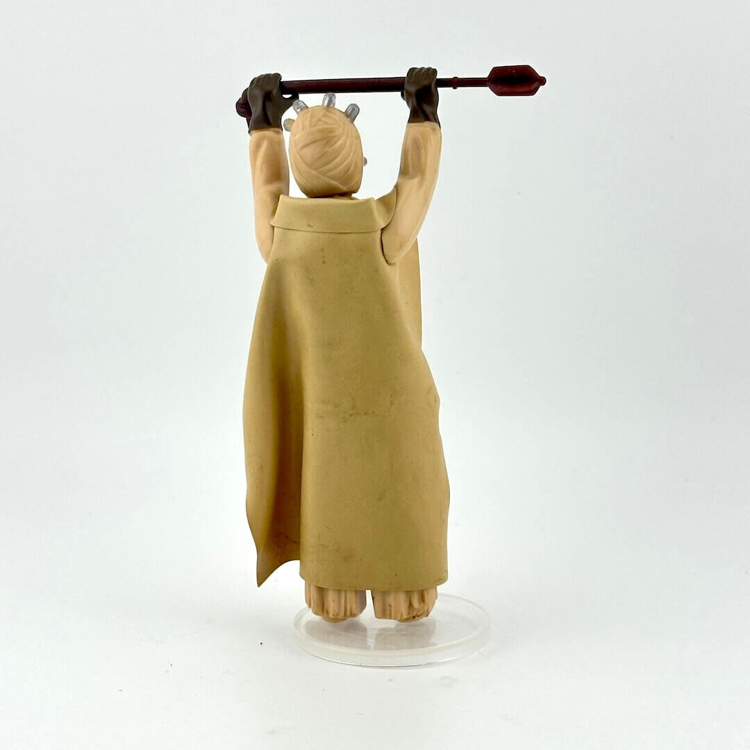 Action figure of Sand Person holding stick aloft in long tan cloak against white background