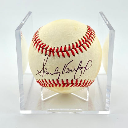 Singed baseball in clear display cube against white background. 