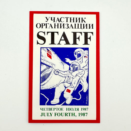 A rectangular printed card featuring Cyrillic text at the top and bottom, a central illustration of an astronaut in a space suit. 