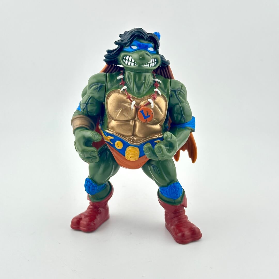 Toy figure of a green turtle with a gold chest piece on a white background