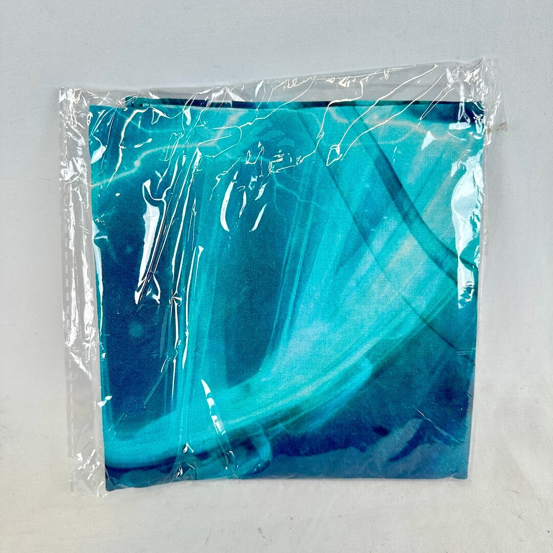 Blue marbled bandana in clear plastic packaging on a light gray background