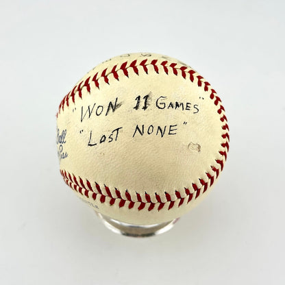 A vintage baseball, featuring black handwritten text that reads 'WON 11 GAMES "LOST NONE"'