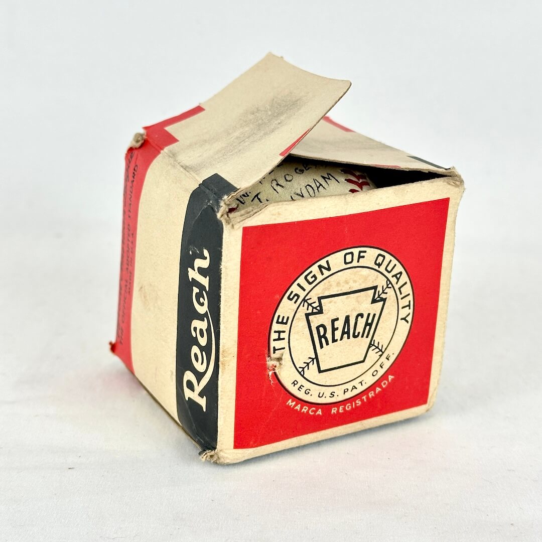 A vintage Reach brand cardboard box with a red front panel, cream sides, and a black vertical stripe.