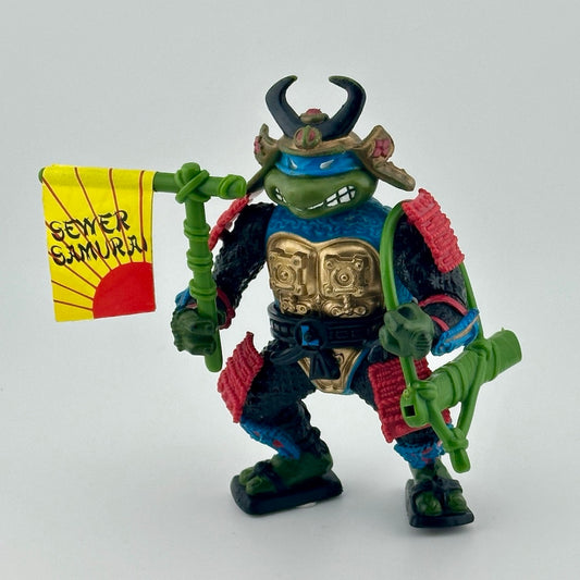 Samurai dressed anthropomorphized turtle with red & blue detailing on armor, green accessories. Front.