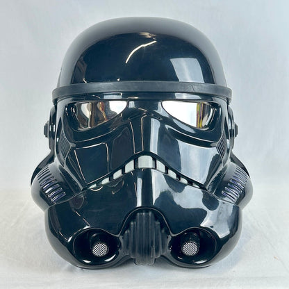 A glossy black Stormtrooper-style helmet photographed against a plain light gray fabric background.