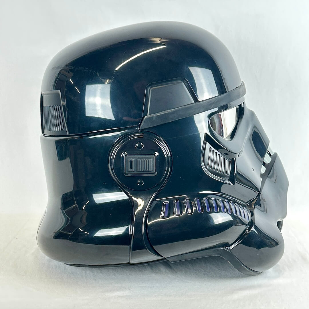 Glossy black stormtrooper helmet photographed from the side on a light background. 