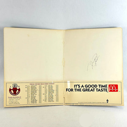 Open folder showing signature on one side and 1985 Chicago Bulls season schedule. 