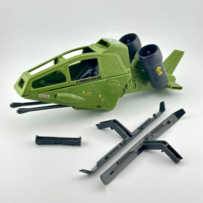A green toy model aircraft with two dark gray jet engines shown with several black plastic accessory pieces placed in front.