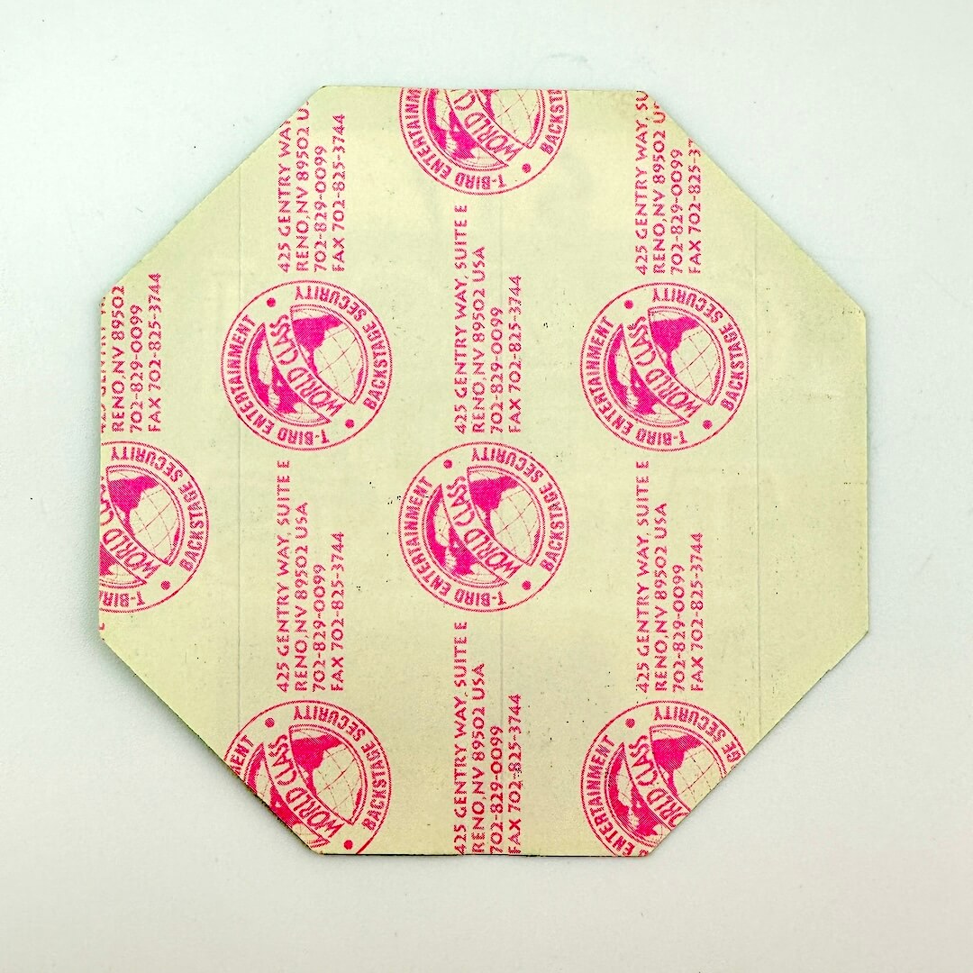 Hexagonal yellow paper with red printed text and logo on a light gray background