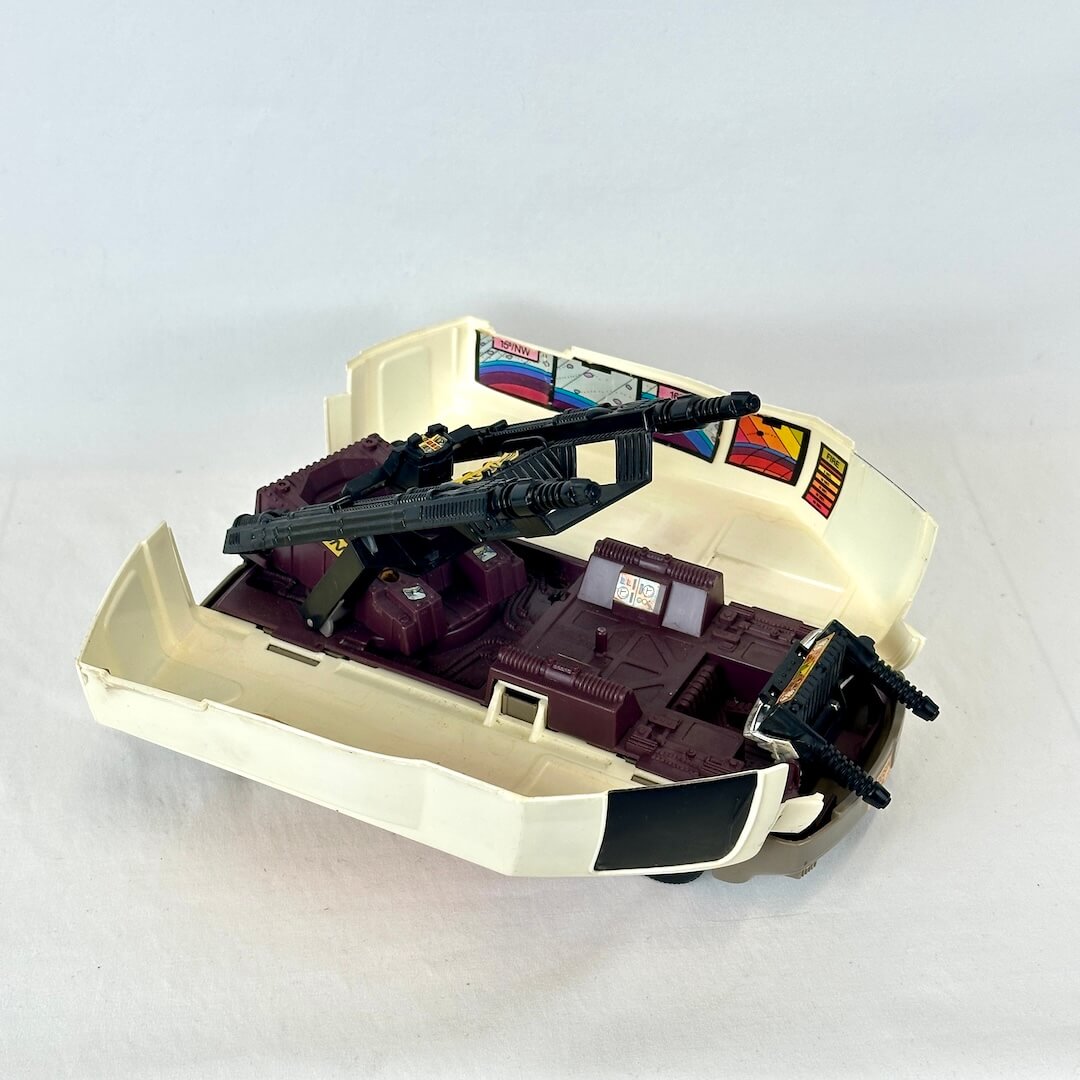 Vintage toy with gun turret extending out of cream colored vehicle shell. 