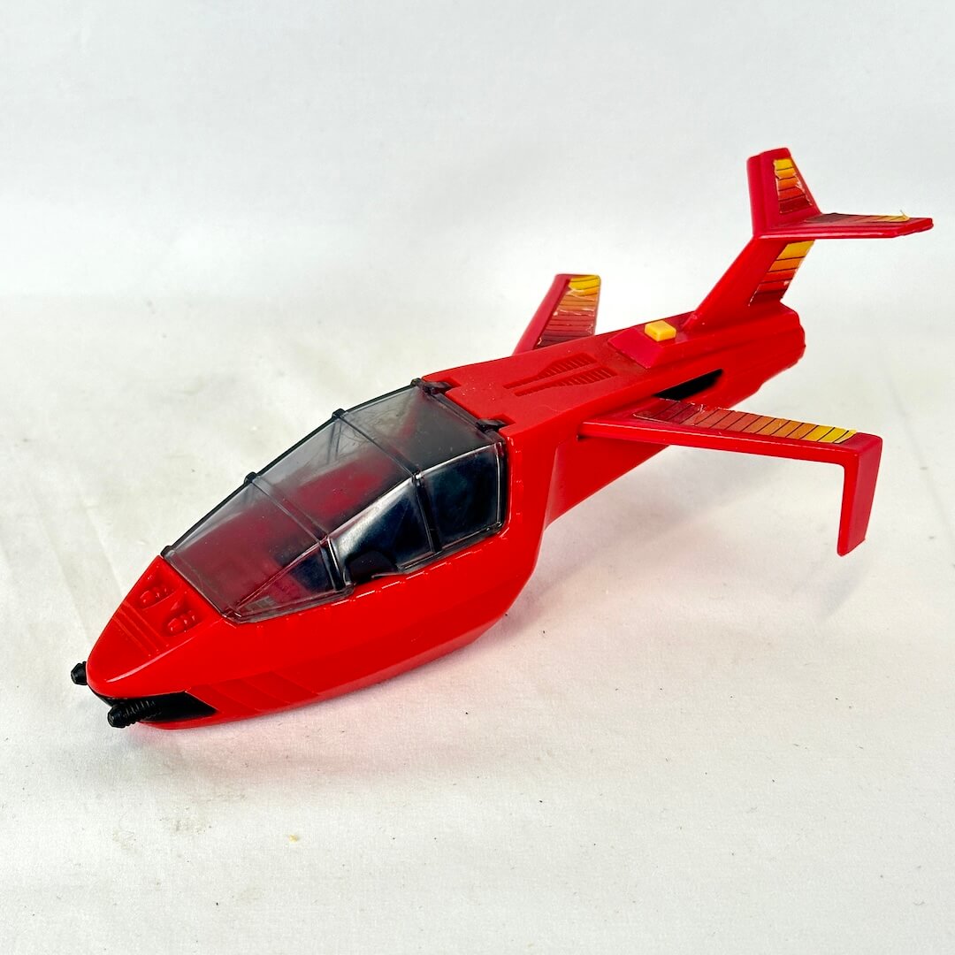 A red toy jet airplane with a clear canopy cockpit and yellow accents on the wings and tail.