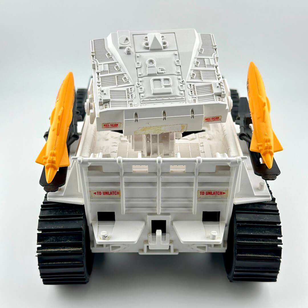 Back view of toy vehicle with missiles and missile box. 