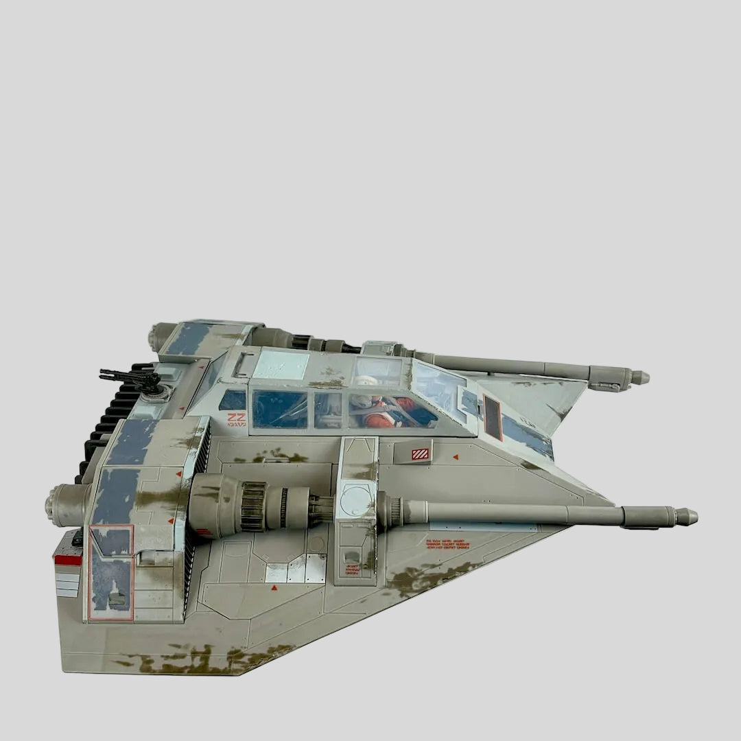 A detailed model toy spacecraft in a weathered gray and beige desert camouflage scheme.