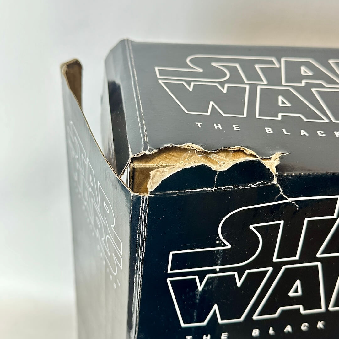 A close-up of a Star Wars The Black Series collectible box, showing a torn cardboard flap on the top edge.
