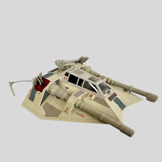 A vintage toy spacecraft, from Star Wars, in a desert sand color with gray and red details.
