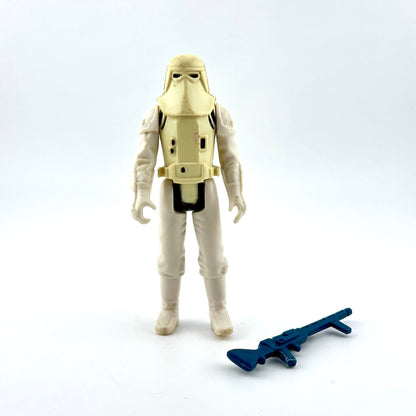 Toy figure of a character in a beige suit with a helmet, holding a blue weapon on a white background