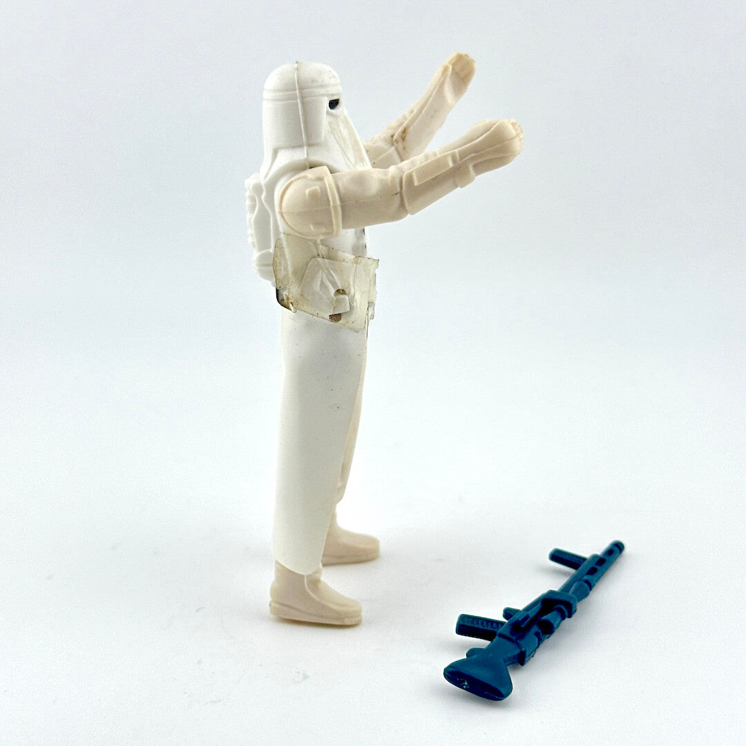 Toy figure of a character in a white suit with a blue weapon on a light gray background
