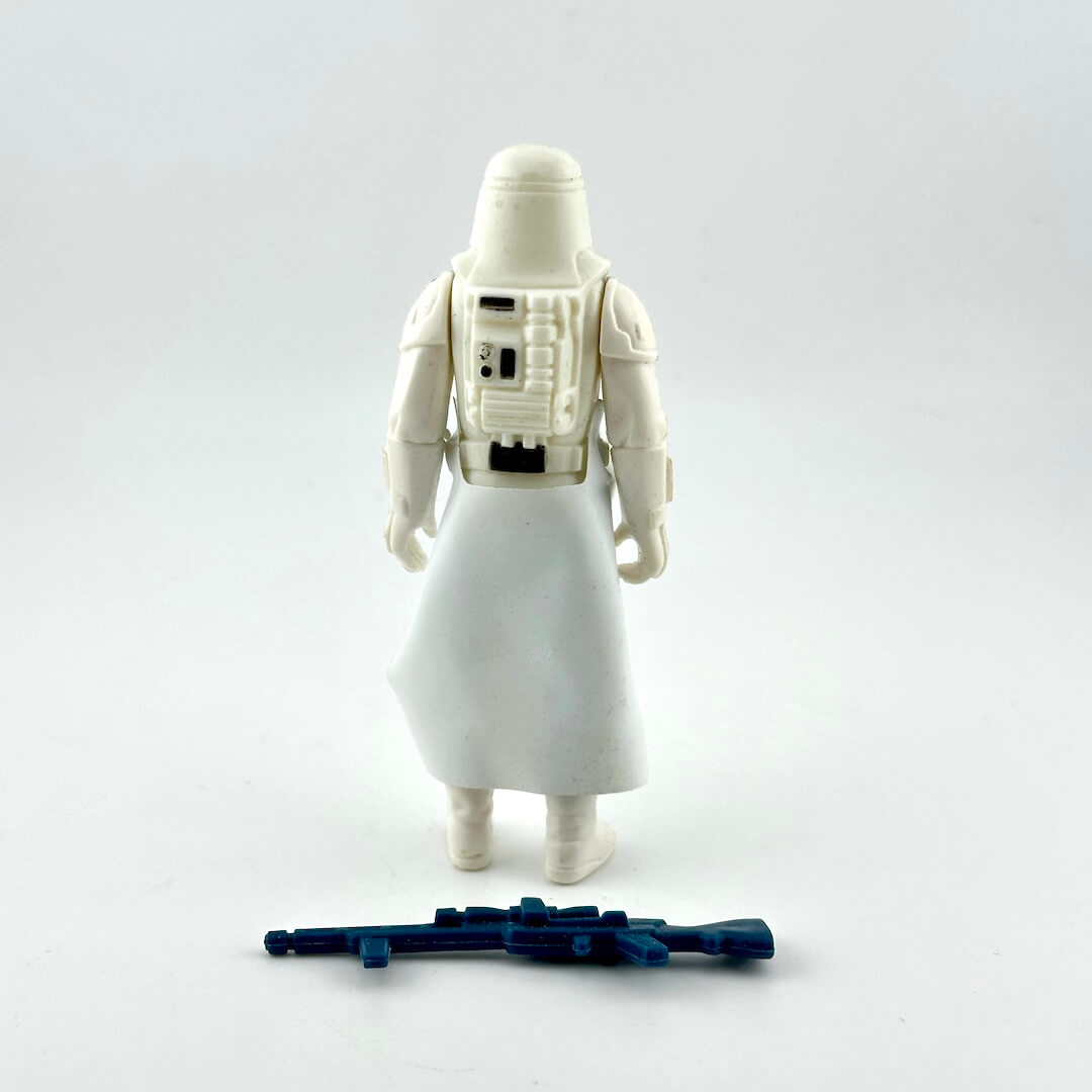A vintage white snowtrooper action figure shown from the back, featuring a detailed back panel and a blue blaster accessory.