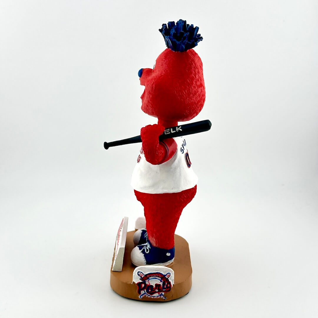 Plush toy figure of a red and white character with a blue hat, holding a bat, on a white background.