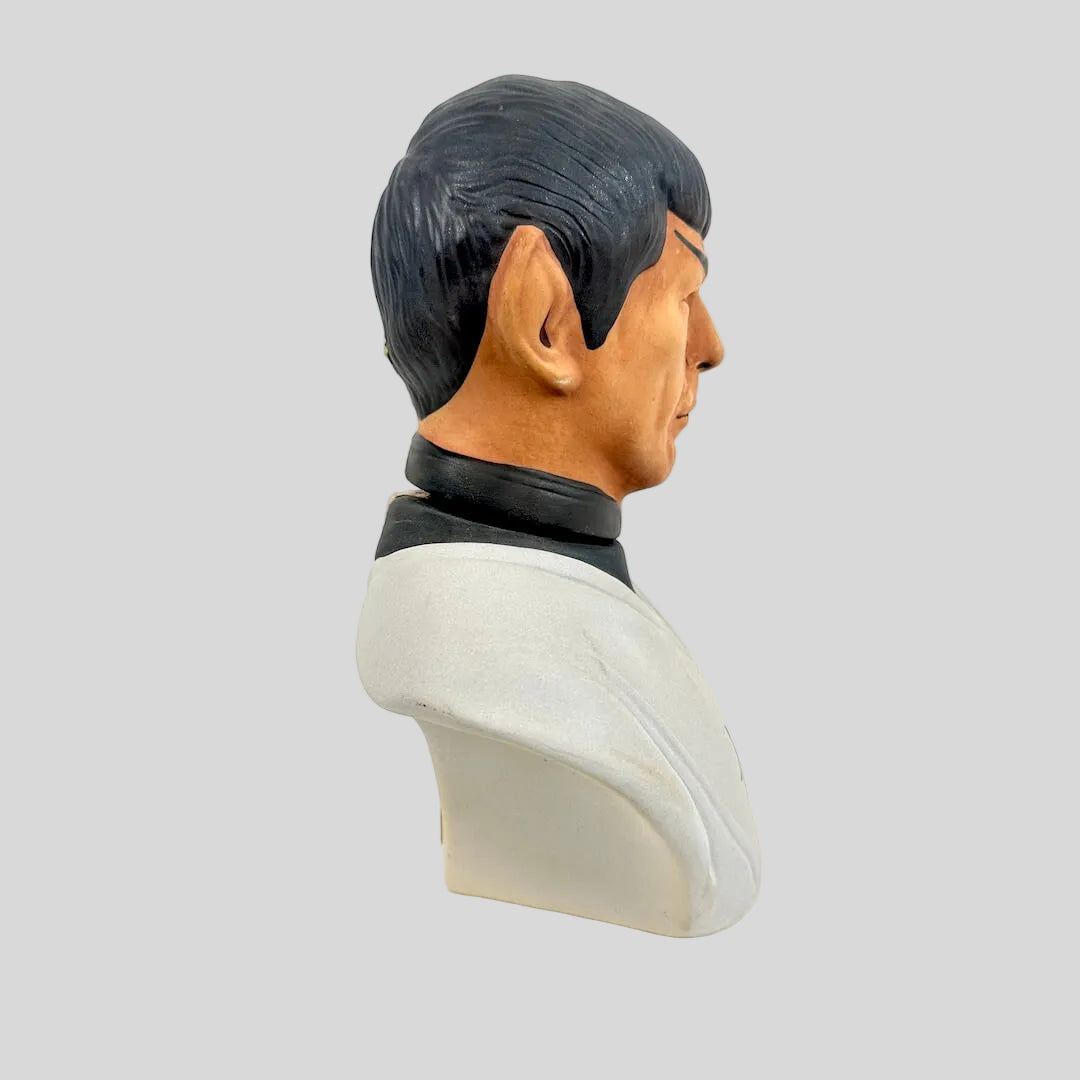 Bust sculpture of a person with dark hair and a light-colored face on a white background