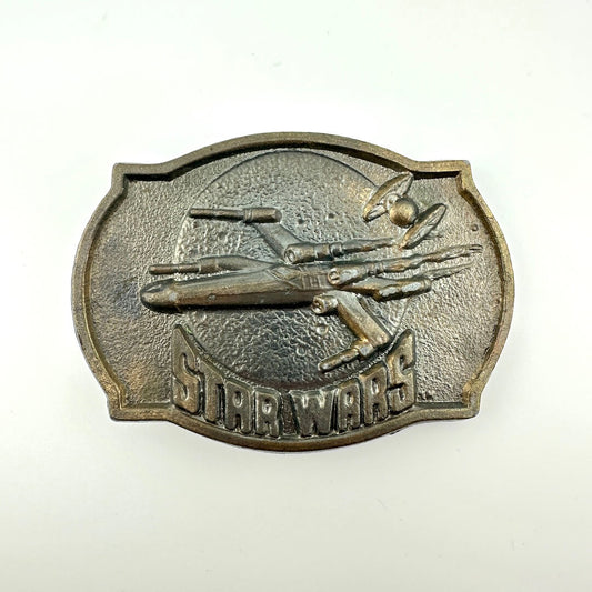 Metallic 'Star Wars' belt buckle with spaceship design on a white background