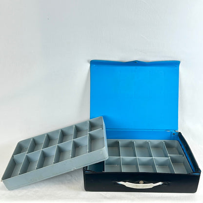 Interior contents of carrying case including two gray trays with dividers inside blue and black case. 