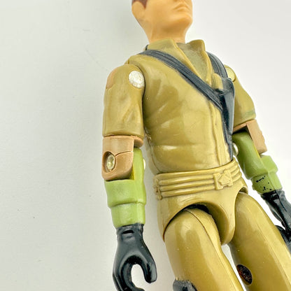 Toy figure in a green and brown outfit on a white background. Close up of crack in left arm. 