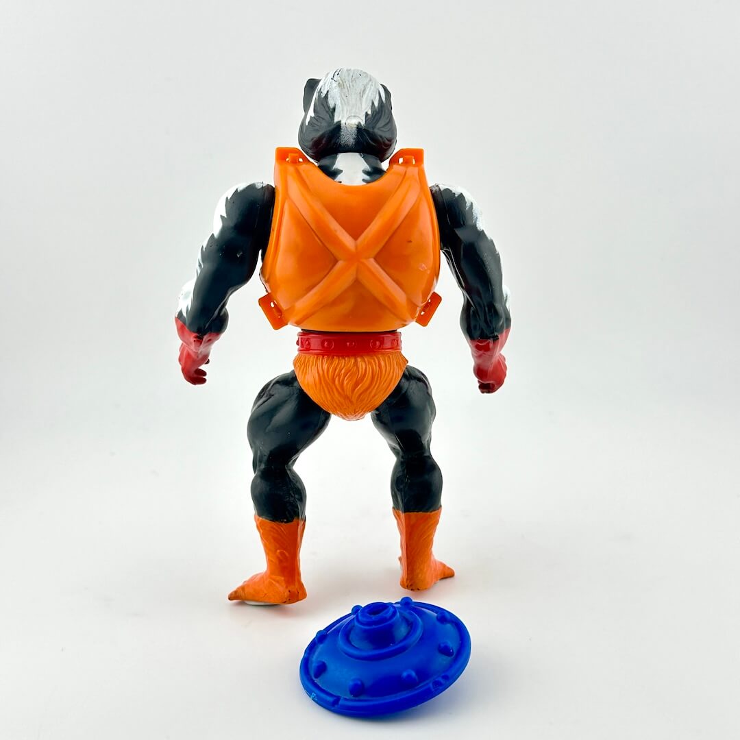 black and white toy action figure with skunk-like features in orange armor with blue shield. 