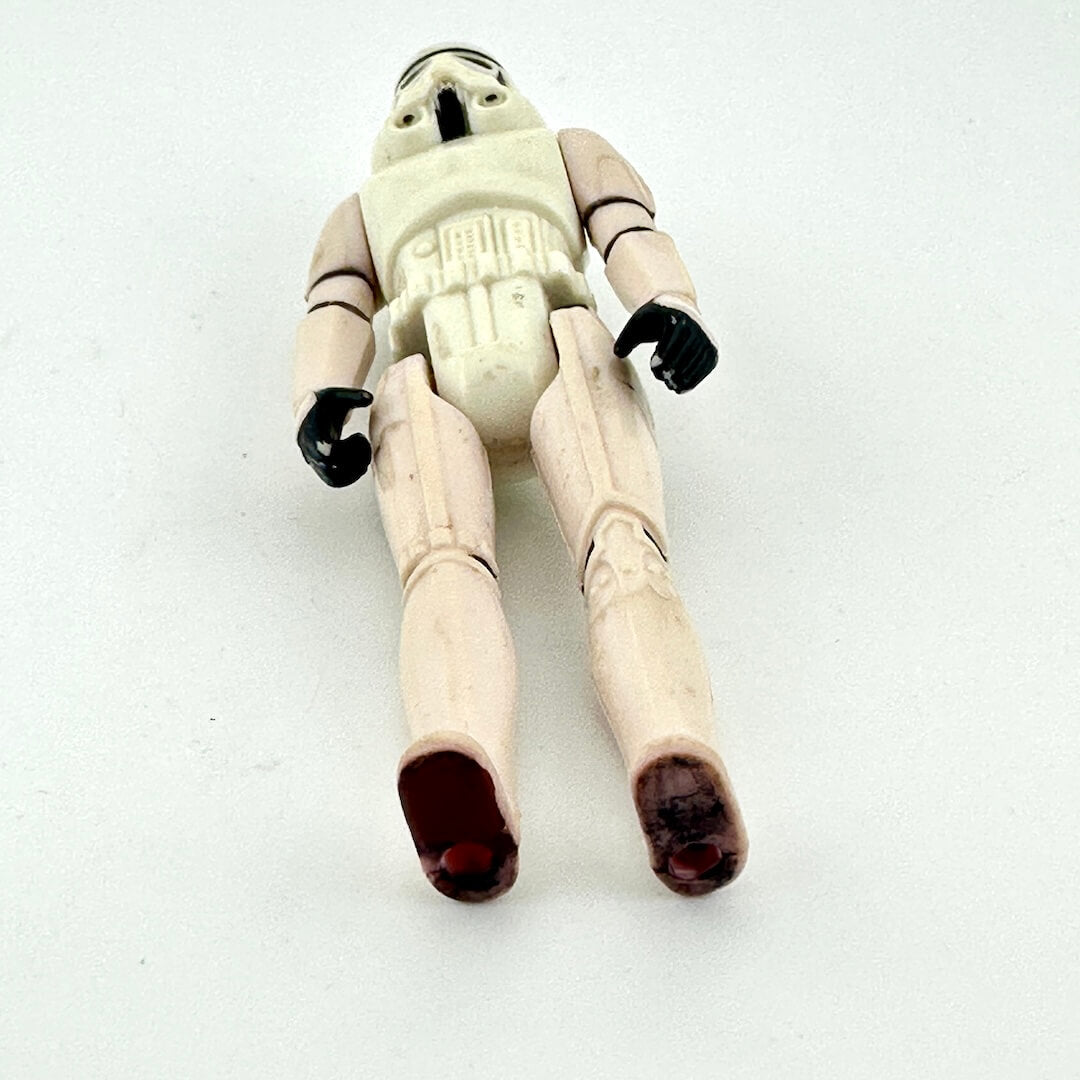 View of action figure from beneath to show markings to bottom of feet and wear on hands. 