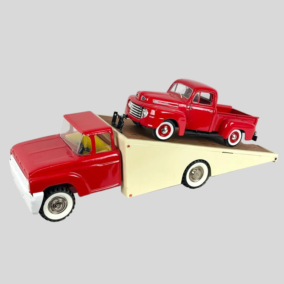 Model of a red truck on top of a beige trailer against a white background