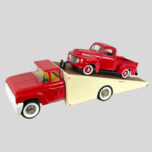 Model of a red truck on top of a beige trailer against a white background