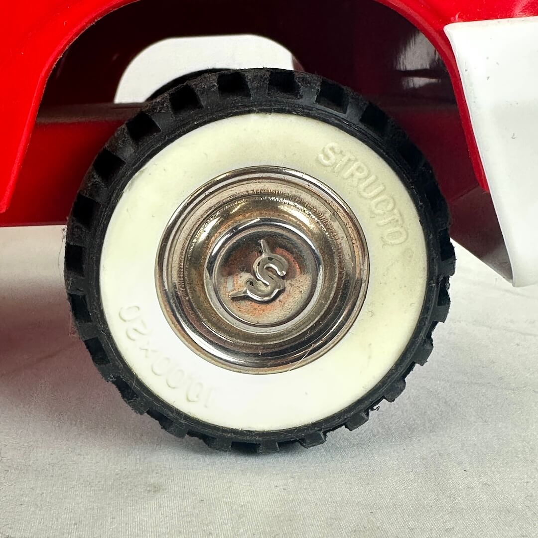 Close-up of a toy car wheel with 'Structo' branding on a white background